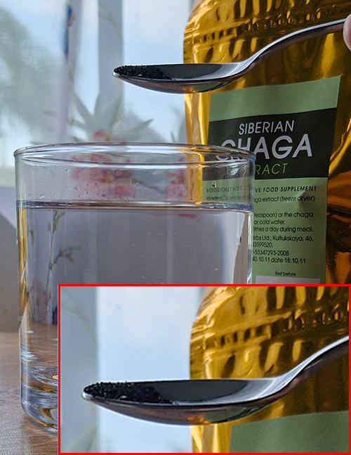 Demonstrating the correct way to sprinkle freeze-dried Chaga extract powder over a glass of water without dipping the spoon.